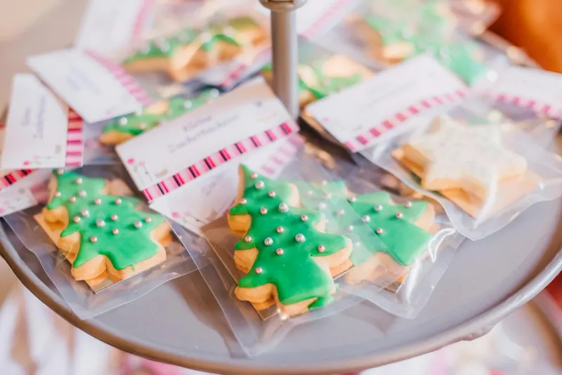 Close-up of decorated Christmas tree cookies with green icing and silver beads on display.